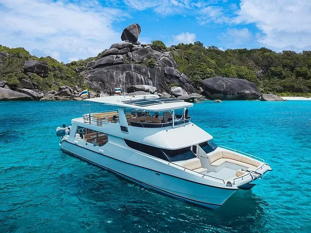 Catamaran ancré dans une eau limpide près d'une côte rocheuse d'île